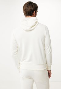 Vit huvtröja med mjuk textur, med dragsko i huvan, ribbade ärmslut och nederdel, designad för en avslappnad passform.