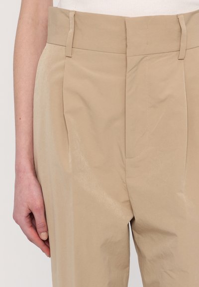 Beige Hosen mit glatter Textur, vorderen Falten, flachem Bund und dezenten Nahtdetails.