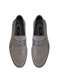 Mocassins en suède gris avec une bande en cuir lisse à l'avant, présentant un bout arrondi et un design minimaliste. Semelle en caoutchouc pour une meilleure traction.