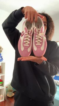 Zapatillas deportivas rosas y blancas con texturas de ante y malla, que presentan un logo de estrella, cordones blancos y una suela de goma color beige.