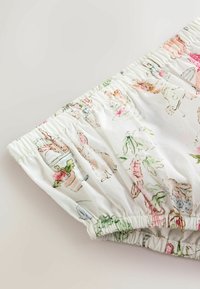 Tissu à bande élastique blanche avec des illustrations pastel de lapins, de carottes, de plantes et d'outils de jardin.