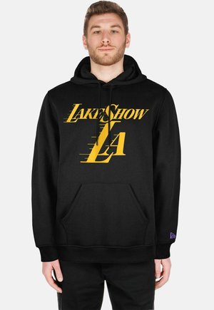 Hoodie noir en tissu doux avec un logo jaune "LakeShow LA" au lettrage dynamique, poche avant et accent violet sur la manche.