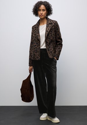 Jakken med leopardprint er i brun og sort stof, hvid bluse, mørke fløjl bukser, brun tote taske og hvide sneakers.