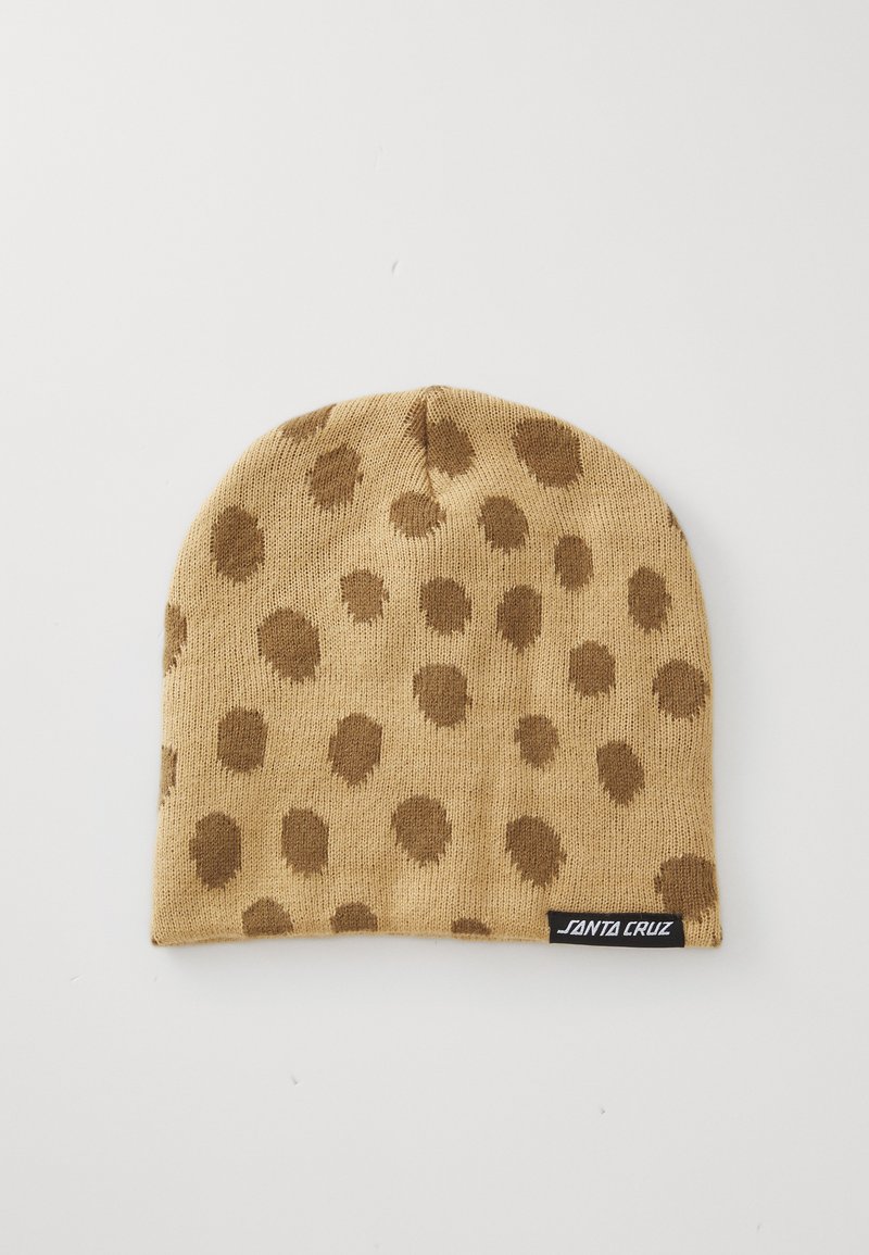 Tan gebreide beanie met een patroon van donkerbruine stippen. Inclusief een zwart label met witte tekst aan de onderrand. Zachte textuur en een aansluitende pasvorm.