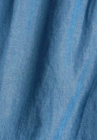 Denimtyg i en mellanmörk blå nyans, med en mjuk textur och subtila tonvariationer samt en svag glans från vävningen.