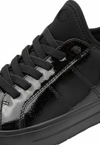 Black patent leather sneaker with textured laces, padded collar, and rubber sole. Features subtle branding on the tongue. Smooth, glossy finish.