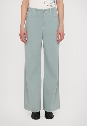 Lichtgroene wijde jeans van denim, met een hoge taille, voorzakken en een nette zoom, gecombineerd met zwarte schoeisel.