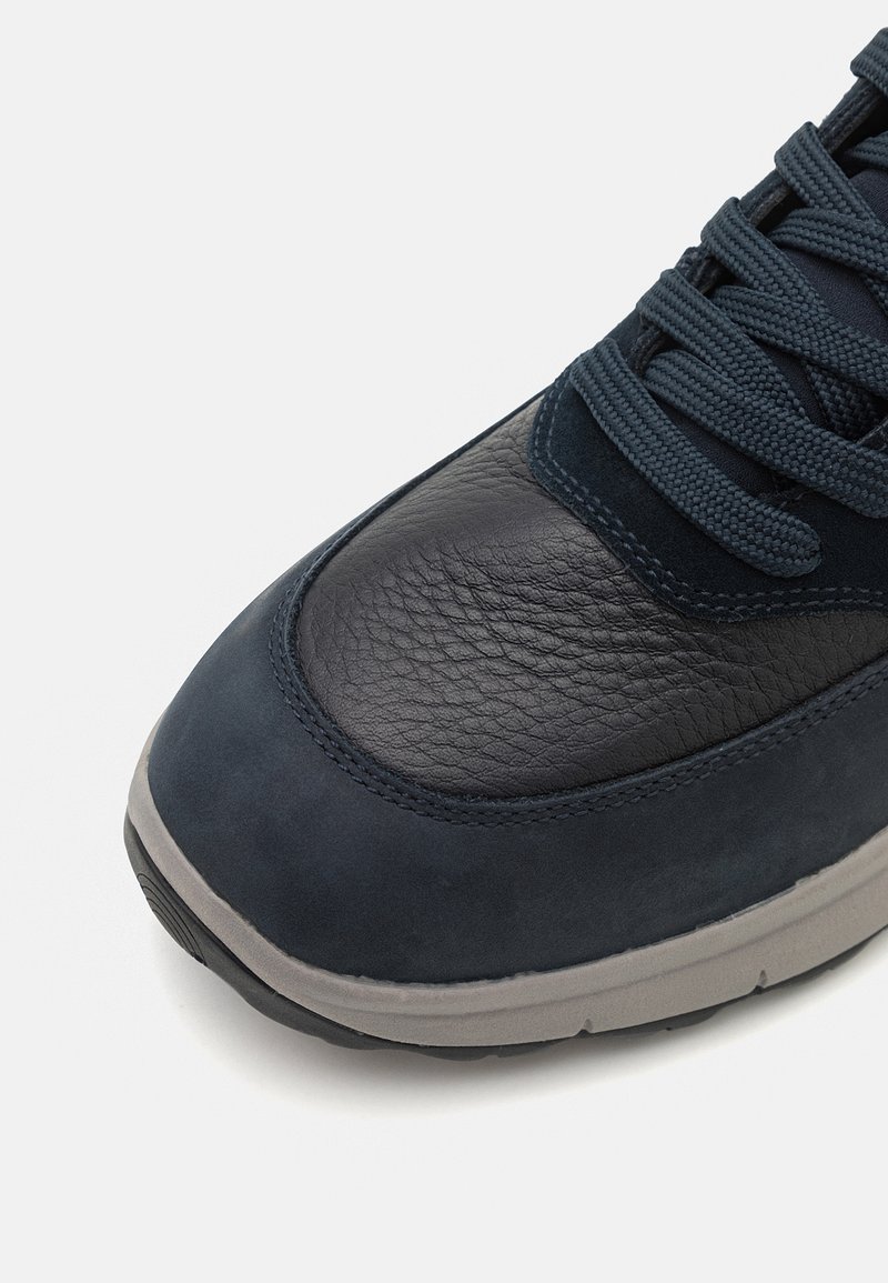 Granatowe sneakersy z teksturowanym noskiem ze skóry, gładką cholewką z zamszu i szarym gumowym podeszewką z wyraźnym wzorem bieżnika.