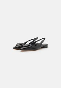 Melnas lakotu ādu slingback flats ar norādītu purngalu, katrā kurpē ir apaļa akcenta detaļa un zems blokveida papēdis.