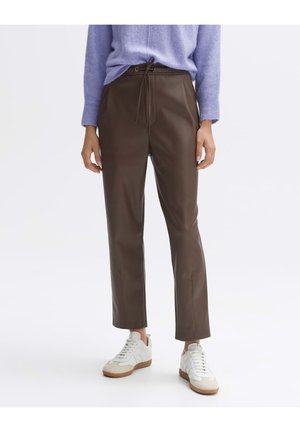 Bruine faux leren broek met een trekkoord in de taille, rechte pasvorm en subtiele glans, gecombineerd met witte sneakers. Zachte textuur, minimalistisch ontwerp.