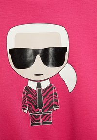 Tecknad karaktär klädd i en rosa zebrarandig kostym, vit skjorta och slips, med mörka solglasögon, mot en rosa bakgrund.