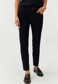 Tumedate denim skinny teksad oranži tikandiga, viie tasku ja nupuga kinnitusega. Kanga tekstuur on sile ja disain on correspondeeriv.