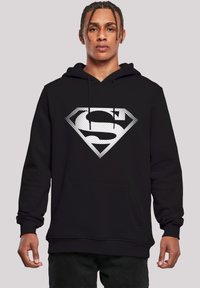 Black hoodie with a large white diamond-shaped graphic featuring an "S" design. Fabric appears soft; includes a front pocket and drawstrings.