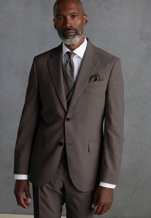 Brown three-piece suit with a textured fabric, featuring a single-button closure, notched lapels, and a green pocket square. Silver tie accent.