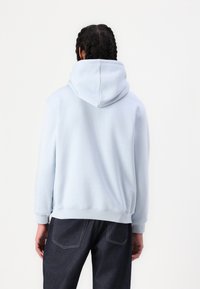 Hellblaues Kapuzensweatshirt mit weicher Textur, gerippten Bündchen und Saum, entspanntem Schnitt und ohne sichtbare Logos oder Muster.