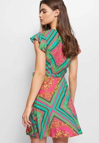 Vestido de manga corta con un vibrante patrón geométrico en rosa, verde y negro. Presenta mangas con volantes, cintura entallada y falda acampanada.