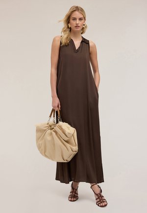 Brown sleeveless maxi dress with a V-neck, side pockets, and smooth fabric. Paired with a large beige bag and strappy black sandals.