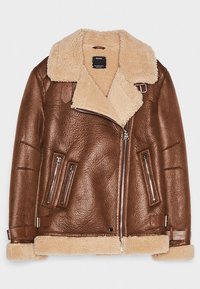 Giacca in pelle marrone con colletto in pelliccia shearling, cerniere laterali e due tasche frontali. Presenta una finitura testurizzata e una fodera in shearling a contrasto.