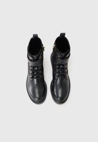 Black leather ankle boots with a smooth texture, gold eyelets, laces, and a side zipper. Features a rounded toe and padded ankle support.