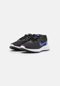 Zapatillas deportivas negras con una parte superior texturizada, swoosh azul de Nike, entresuela blanca y suela de goma negra. Lazos y collar acolchado visibles.