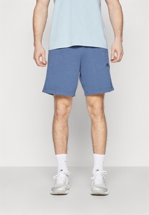 Shorts de sport bleus en tissu doux avec une coupe décontractée, ornés d'un logo discret sur le côté. Associez-les à des chaussettes blanches et des baskets.
