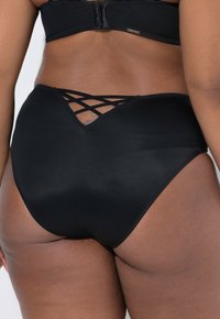 Hoge taille zwarte panties gemaakt van gladde stof, met een kruislingse ontwerp aan de achterkant en zachte elastische afwerking.