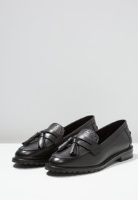Zwarte leren loafers met decoratieve kwastjes en geperforeerde accenten. Beschikt over een stevige zool en een gladde afwerking. Rond neusvorm.