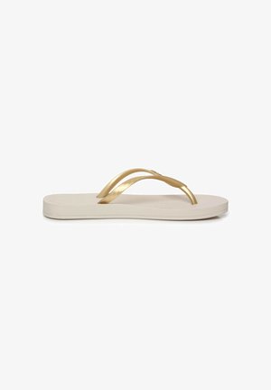Infradito beige con suola piatta e cinturini metallici dorati a forma di Y.