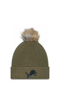 Cappello di lana verde oliva con risvolto, caratterizzato da un pompon in pelliccia sintetica sulla sommità e un emblema scuro di un leone sul davanti.