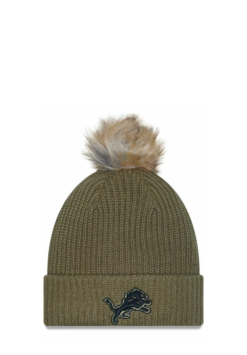 Cappello di lana verde oliva con risvolto, caratterizzato da un pompon in pelliccia sintetica sulla sommità e un emblema scuro di un leone sul davanti.