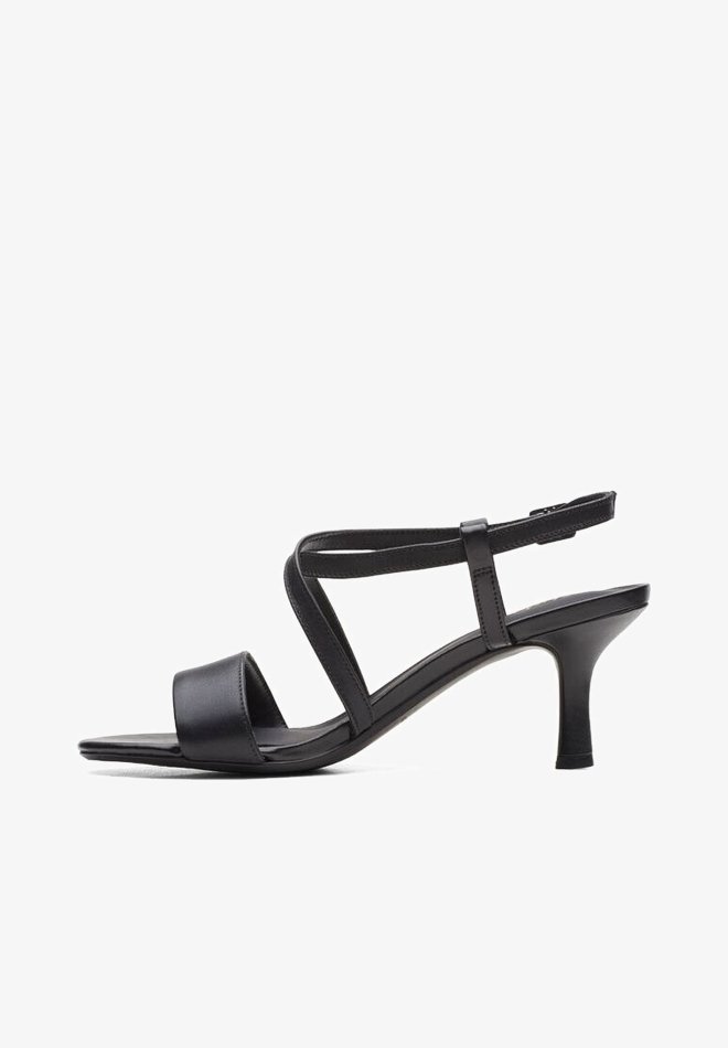 Sandale à talon en cuir noir avec une large bride avant, des lanières croisées à la cheville et un talon fin. Texture lisse avec un design minimaliste.
