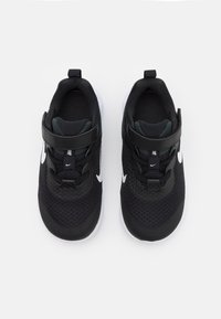 Černé sportovní boty s textilním svrškem, zdobené texturou, polstrovaným límcem a bílým logem Nike Swoosh na každé straně.