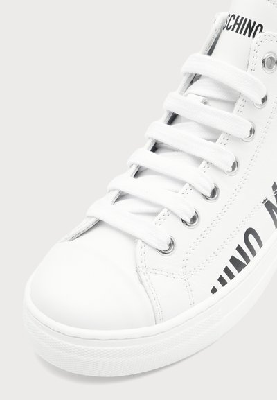 Baskets montantes blanches avec lacets blancs, œillets métalliques et texte noir partiel indiquant "MOSCHINO" sur le côté.