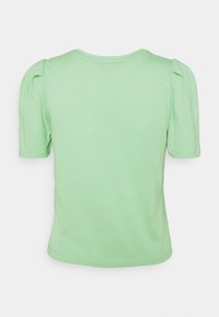 Light green short-sleeve t-shirt made of soft cotton. Features puffed cap sleeves and a classic crew neckline. Smooth texture, simple design.