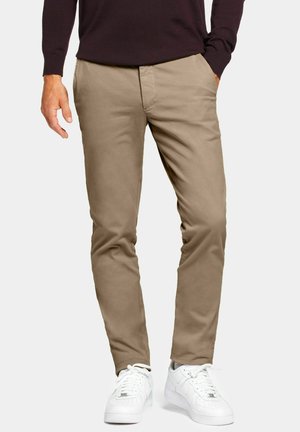 Chinos beiges en coton, à coupe droite, avec deux poches latérales et une texture lisse, assortis à des baskets blanches.