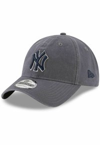 Grå baseballcaps med en buet skygge. Har en stor brodert NY-logo i marineblå. Justerbar stropp bak med et teksturert stoff.
