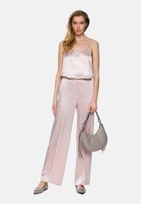 Pink satin camisole with thin straps paired with palazzo trousers. Accessory includes a gray handbag with fringe details. Silver flats complete the look.