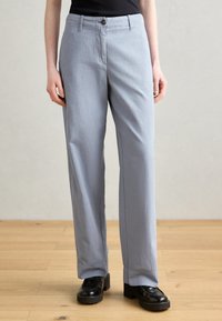 Light gray, loose-fitting trousers with a straight leg design, button closure, and side pockets. Fabric has a smooth texture.