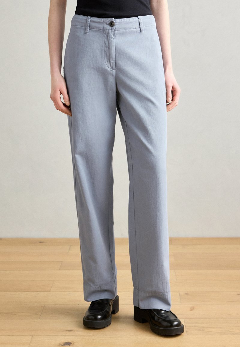 Light gray, loose-fitting trousers with a straight leg design, button closure, and side pockets. Fabric has a smooth texture.