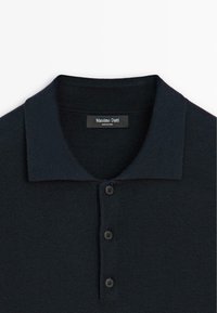 Marineblå polo shirt med struktureret strik, med krave og tre sorte knapper. Etiketten siger "Massimo Dutti."