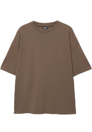 Barna, túlméretes pamut póló. Rövid ujjú, kerek nyakkivágással rendelkezik, és finom logó hímzés található rajta, azonos árnyalatban.