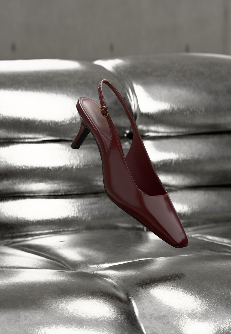 Roter Slingback-Schuh aus Lackleder mit spitzer Zehenpartie und kleinem Absatz, versehen mit einem goldfarbenen Akzent nahe dem Knöchelriemen.