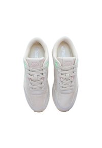 Sneakers med en ljusbeige meshuverdel och mockadetaljer, med gröna och rosa öglor, samt en texturerad gummisula. Minimalistisk design.