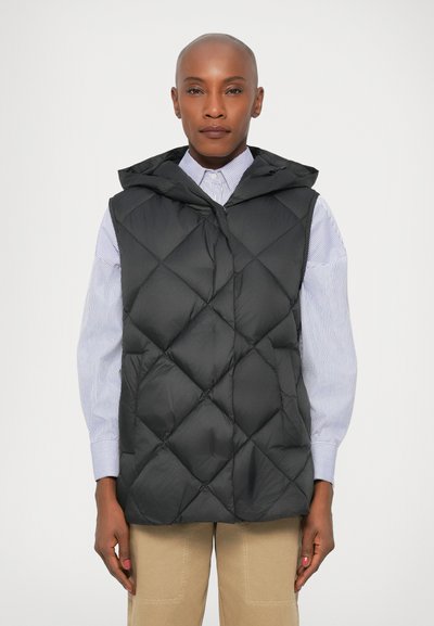 Vest negru căptușit cu glugă, model pătrățes ce măsoară, material ușor. Purtați peste o cămașă cu dungi albastre deschise.