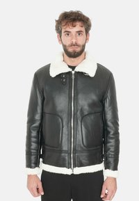 Giubbotto di pelle nera con colletto e polsini in finta pelliccia bianca. Presenta una chiusura con zip e due tasche frontali. Texture liscia, vestibilità su misura.