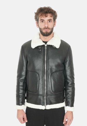 Giubbotto di pelle nera con colletto e polsini in finta pelliccia bianca. Presenta una chiusura con zip e due tasche frontali. Texture liscia, vestibilità su misura.
