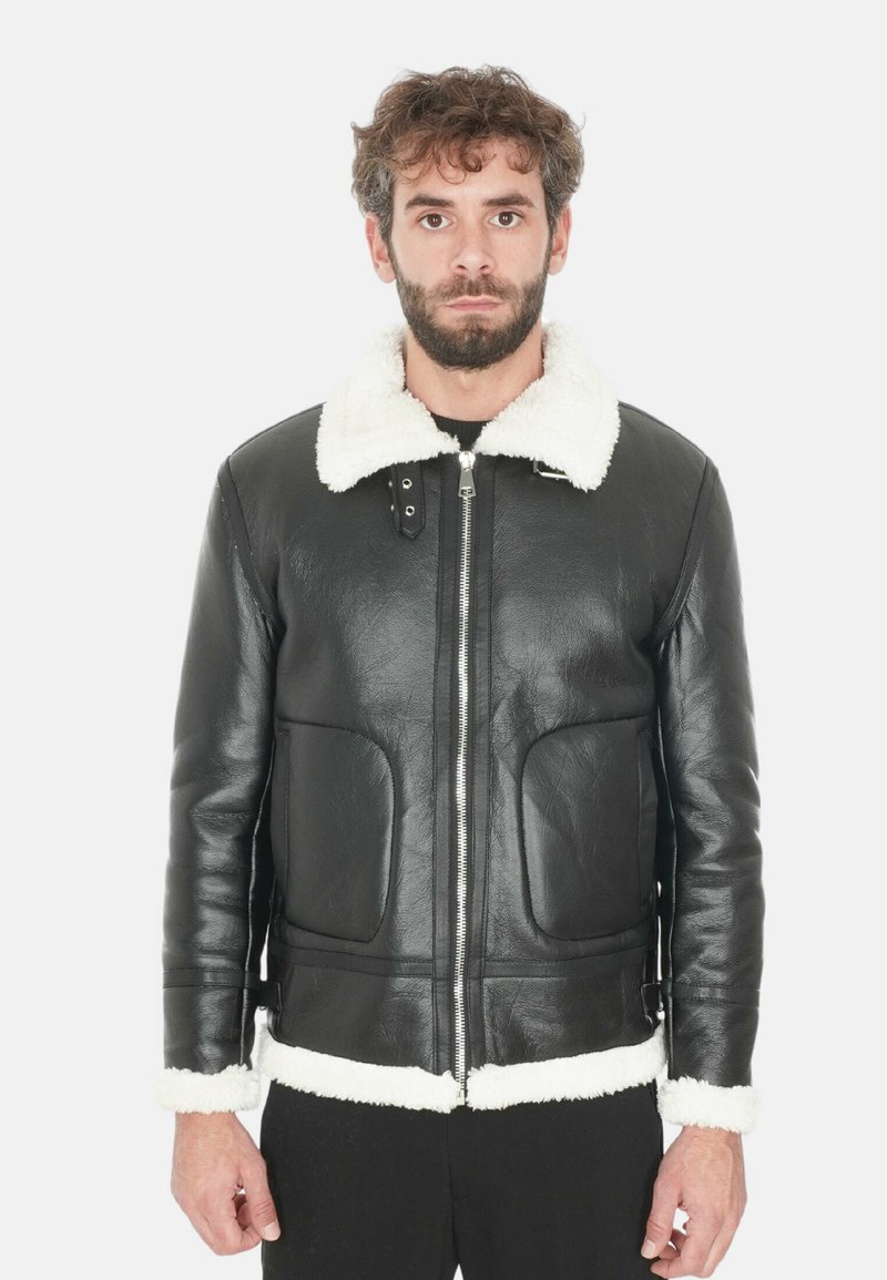 Giubbotto di pelle nera con colletto e polsini in finta pelliccia bianca. Presenta una chiusura con zip e due tasche frontali. Texture liscia, vestibilità su misura.