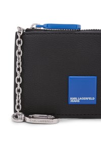 Neceser negro texturizado con cremallera y cadena plateada, parche cuadrado azul con la inscripción "KARL LAGERFELD JEANS" y tirador de cremallera a juego en azul.