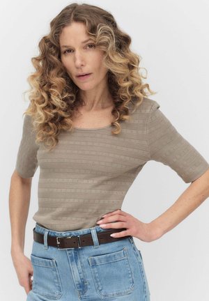 Beige tekstureret striktop med korte ærmer og kvadratisk udskæring. Kombineret med lyseblå højtaljede jeans og et brunt bælte.