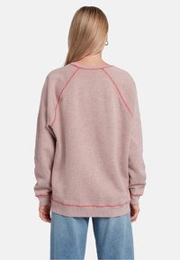Sweatshirt rose avec manches raglan, col rond et couture rouge contrastante le long des coutures. Ajustement doux et décontracté ; vue arrière montrée.